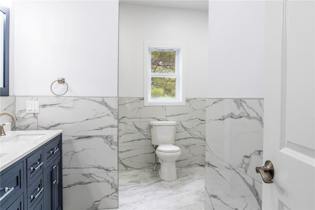 bathroom with vanity, toilet, and tile walls