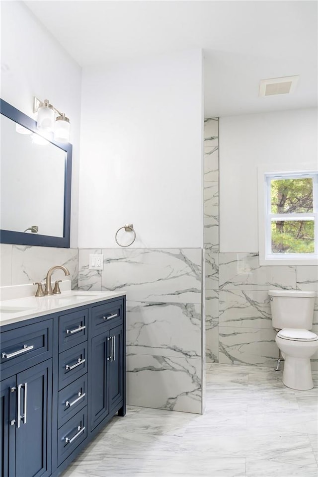 bathroom with vanity, toilet, and tile walls