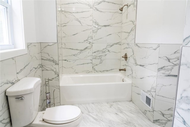 bathroom with shower / washtub combination, toilet, and tile walls