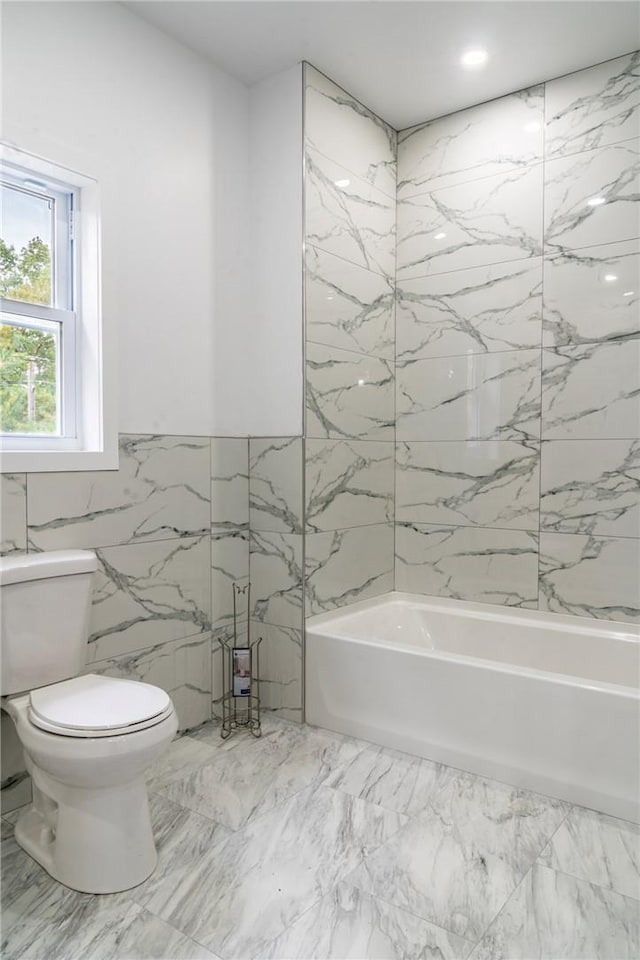 bathroom with tiled shower / bath combo, tile walls, and toilet