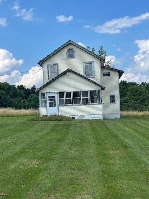 back of house featuring a sunroom and a lawn