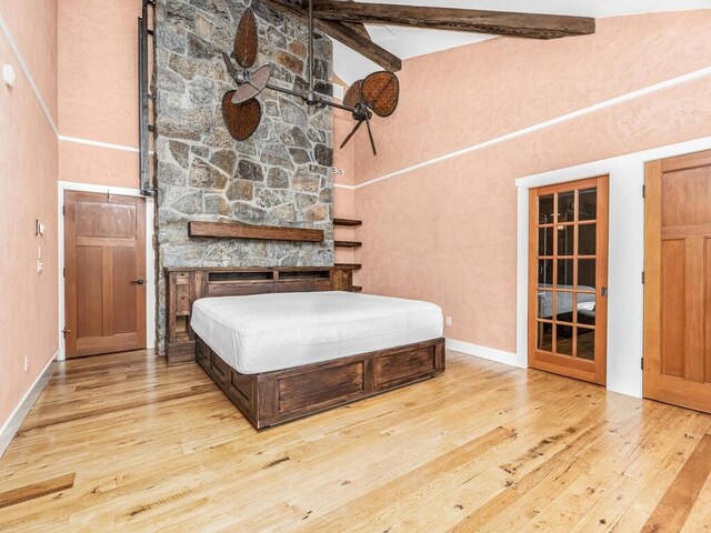 bedroom with beamed ceiling, high vaulted ceiling, and hardwood / wood-style flooring