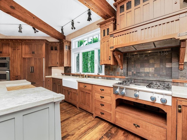 kitchen with appliances with stainless steel finishes, backsplash, sink, beam ceiling, and hardwood / wood-style floors