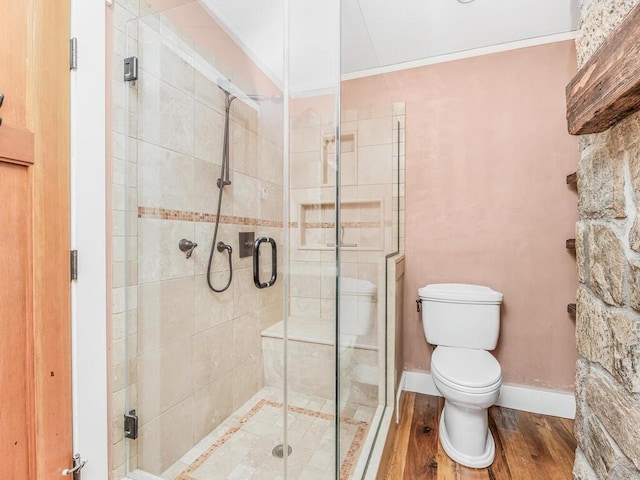 bathroom with hardwood / wood-style floors, toilet, ornamental molding, and a shower with shower door