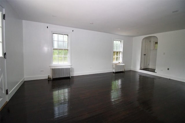 unfurnished room with plenty of natural light, dark hardwood / wood-style flooring, and radiator