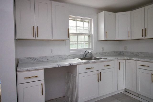 kitchen featuring tile patterned flooring, light stone counters, white cabinetry, and sink