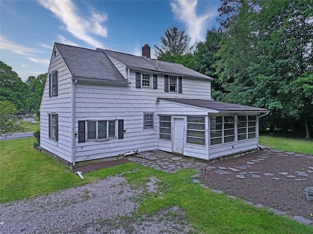 rear view of house with a lawn and a sunroom