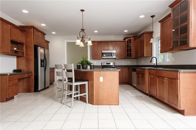 kitchen with sink, appliances with stainless steel finishes, decorative light fixtures, a kitchen island, and a chandelier