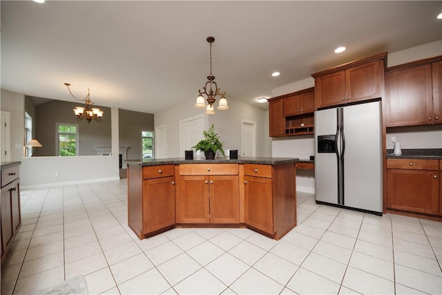 kitchen with white refrigerator with ice dispenser, pendant lighting, light tile patterned floors, a notable chandelier, and a kitchen island