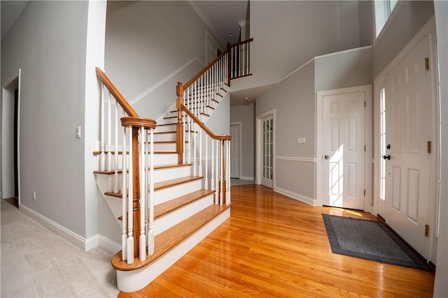 foyer entrance with light hardwood / wood-style flooring and a towering ceiling