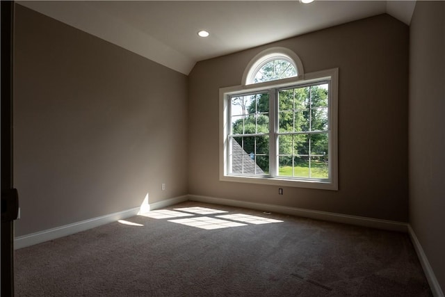 carpeted spare room with vaulted ceiling