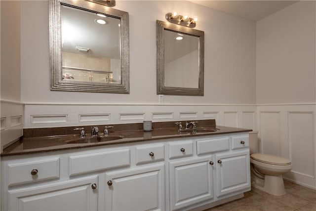 bathroom featuring tile patterned flooring, vanity, toilet, and a shower with shower door