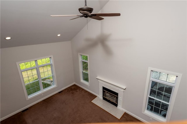 unfurnished living room featuring plenty of natural light, dark carpet, and ceiling fan