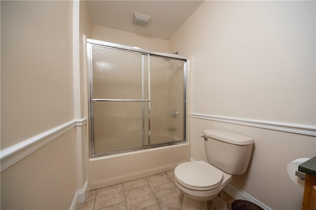 bathroom with tile patterned flooring, combined bath / shower with glass door, and toilet