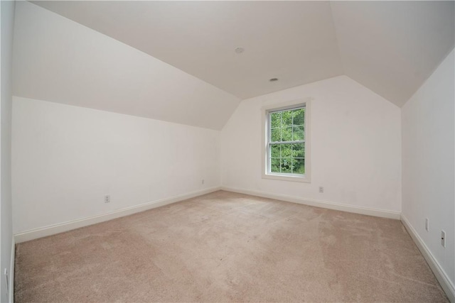 bonus room with light colored carpet and vaulted ceiling