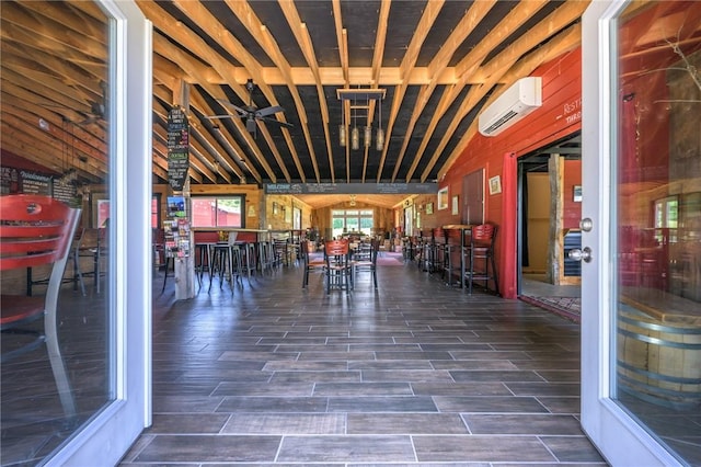 unfurnished dining area featuring a wall mounted AC, ceiling fan, dark hardwood / wood-style flooring, and vaulted ceiling