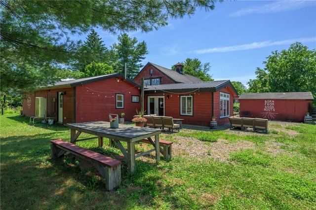 rear view of property with a lawn, an outdoor living space, and french doors