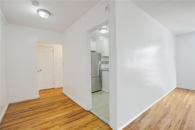 corridor with light hardwood / wood-style floors and ornamental molding