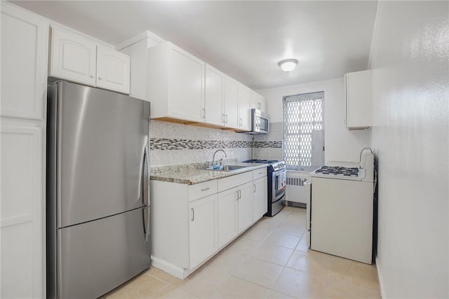 kitchen featuring tasteful backsplash, stainless steel appliances, sink, light tile patterned floors, and white cabinetry