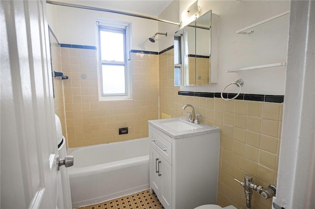 full bathroom featuring vanity, tiled shower / bath combo, toilet, and tile walls