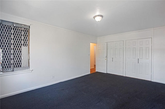 unfurnished bedroom with carpet flooring, multiple closets, and crown molding