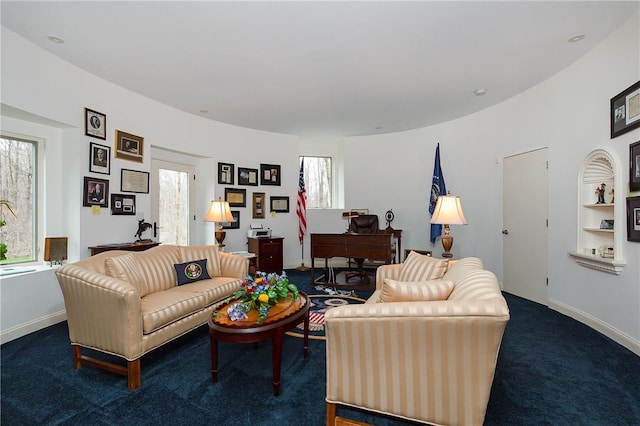 living room featuring dark colored carpet and a wealth of natural light