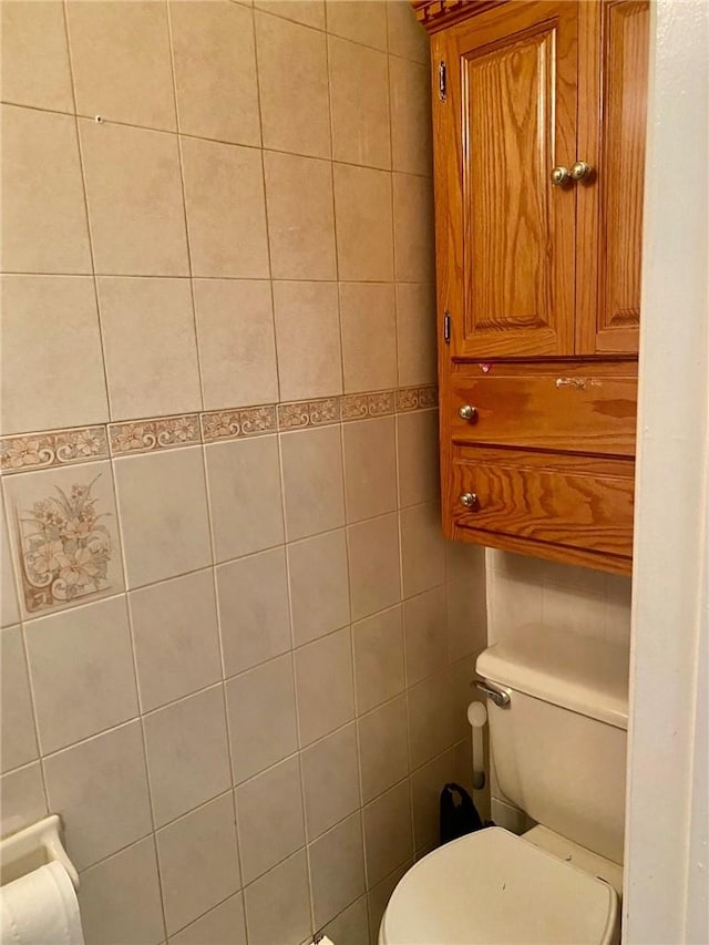 bathroom featuring tile walls and toilet