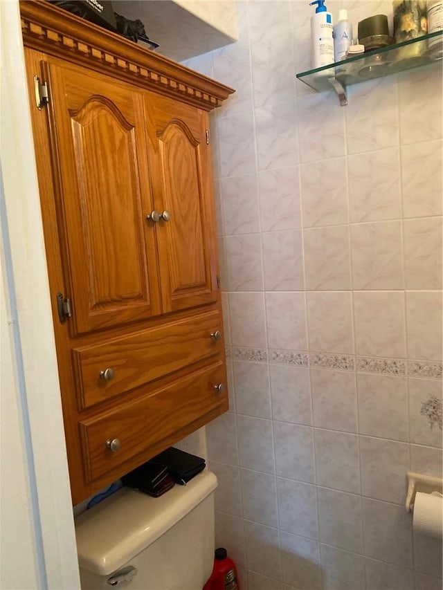 bathroom featuring toilet and tile walls