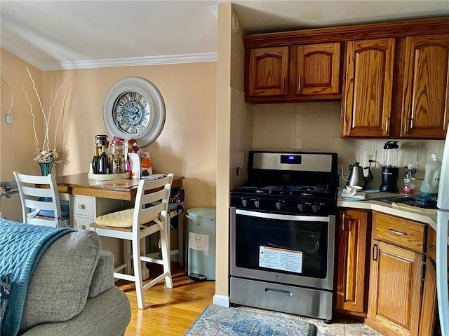 3664 Palmer Ave, Bronx, NY 10466 - kitchen featuring stainless steel range with gas stovetop, ornamental molding, tasteful backsplash, brown cabinetry, and light wood finished floors