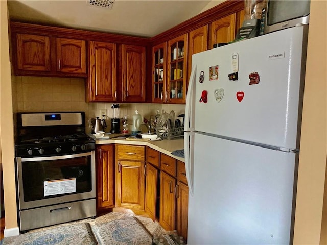 3664 Palmer Ave, Bronx, NY 10466 - kitchen with freestanding refrigerator, gas stove, light countertops, glass insert cabinets, and decorative backsplash