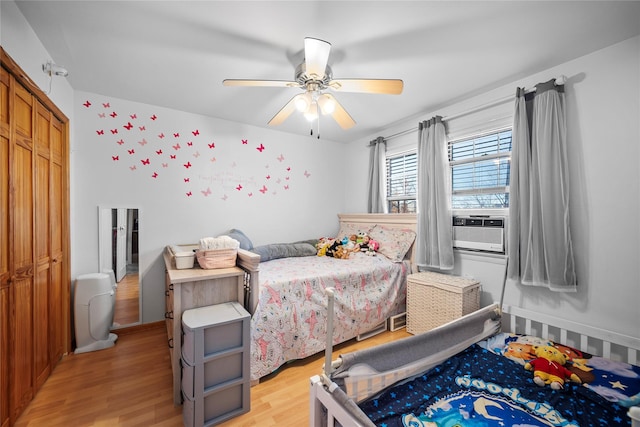 bedroom with a closet, light hardwood / wood-style flooring, ceiling fan, and cooling unit