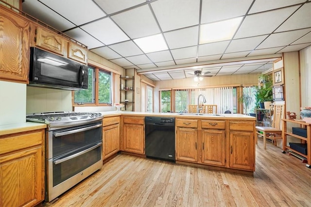 kitchen with ceiling fan, sink, kitchen peninsula, black appliances, and light wood-type flooring