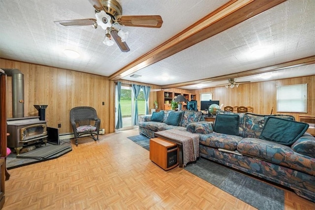 living room with a wood stove, a textured ceiling, and wooden walls