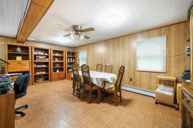 dining space with a wealth of natural light, wood walls, and a baseboard heating unit