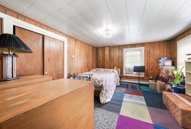 carpeted bedroom with wood walls and a baseboard heating unit