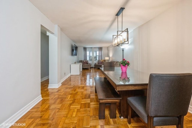 dining room featuring a chandelier and light parquet flooring