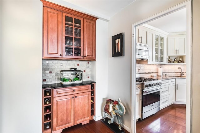 kitchen featuring backsplash, dark stone counters, dark wood-type flooring, white cabinetry, and stainless steel appliances