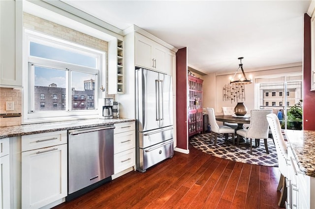 kitchen with light stone countertops, hanging light fixtures, dark wood-type flooring, stainless steel appliances, and white cabinets