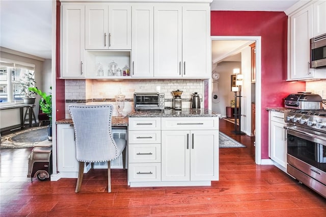 kitchen with white cabinets, stainless steel appliances, dark wood-type flooring, and dark stone countertops