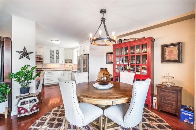 dining area with sink, dark hardwood / wood-style floors, and a notable chandelier