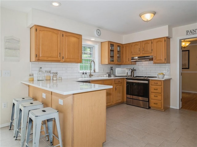 kitchen featuring electric range, white microwave, glass insert cabinets, a peninsula, and light countertops