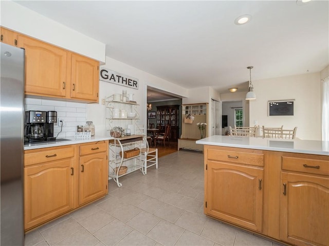 kitchen with freestanding refrigerator, light countertops, hanging light fixtures, and backsplash