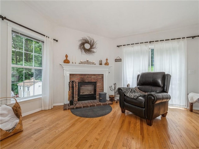 living area featuring light wood-style floors, a fireplace, and baseboards