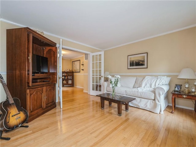 living room featuring light wood-style floors, baseboards, crown molding, and french doors