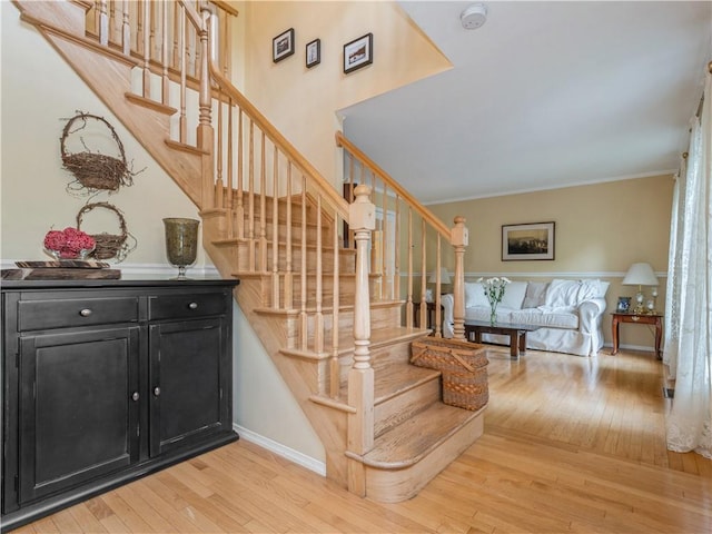 stairs with crown molding, baseboards, and wood finished floors