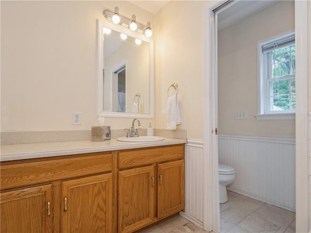 bathroom with wainscoting, vanity, toilet, and tile patterned floors