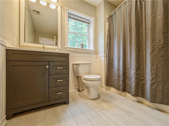 bathroom with visible vents, toilet, vanity, wood finished floors, and a shower with curtain