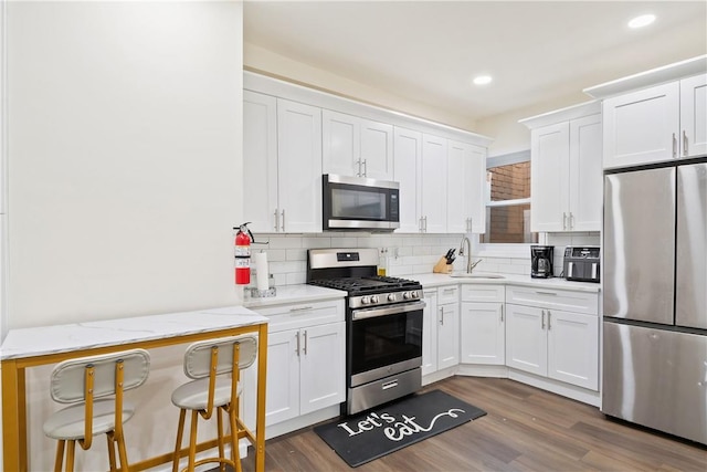 kitchen with light stone countertops, white cabinets, stainless steel appliances, and dark hardwood / wood-style floors