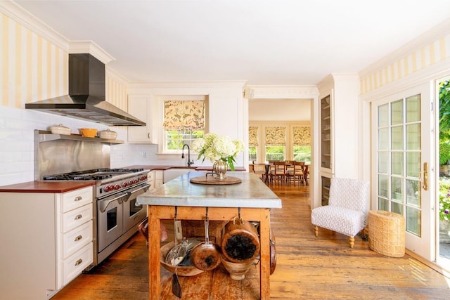 20 Smithfield Way, Amenia, NY 12501 - kitchen with wall chimney exhaust hood, double oven range, dark wood-type flooring, white cabinetry, and ornamental molding