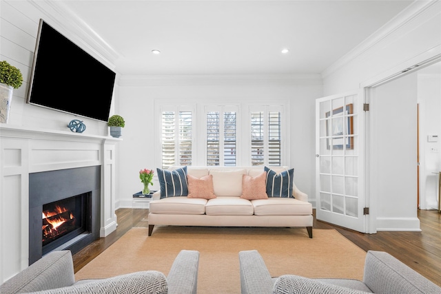 living area featuring a warm lit fireplace, ornamental molding, wood finished floors, and baseboards